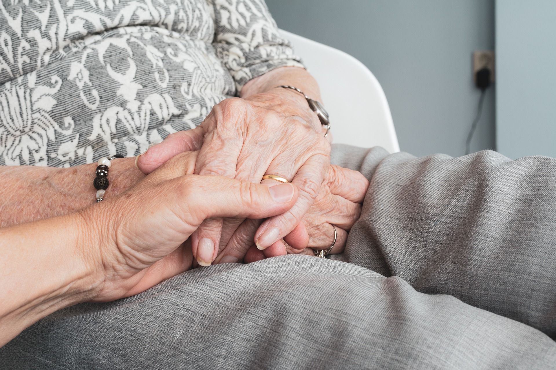 Polnische Pflegekraft hält die Hand einer Seniorin