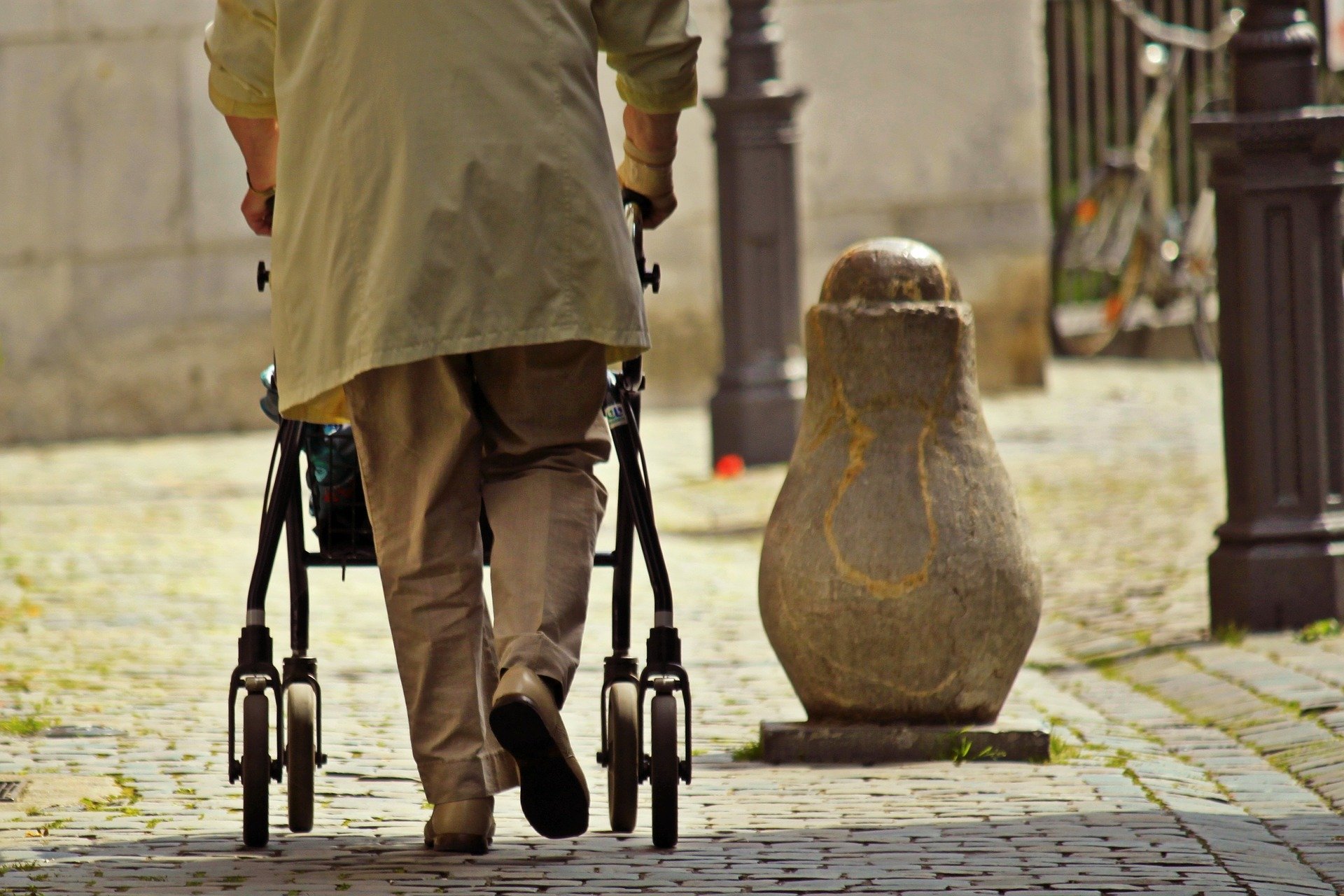 Senior mit Gehhilfe läuft eine Straße entlang